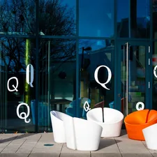 Modern chairs outside a glass building with letter q related to Transform Your Home with Modern Entryway Furniture