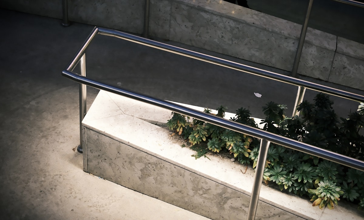 Modern metal railing beside concrete planter with plants related to Essential Guide to Bed Safety