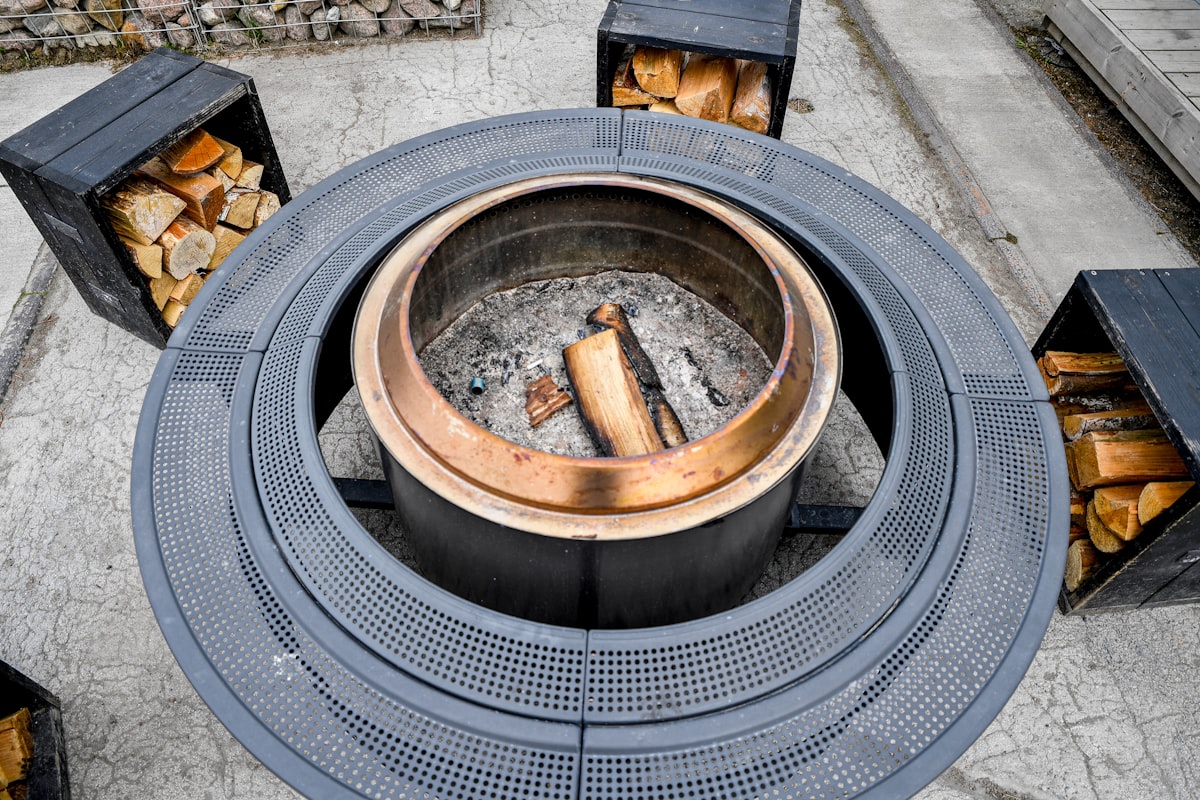 Nordic Coziness: A modern circular outdoor fire pit with stacked firewood at Iglupark in the Noblessner district of Tallinn, Estonia. related to Choosing the Perfect Patio Heater: Cast Iron or Clay Chiminea?