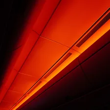 Orange light illuminates a dark ceiling panel related to The Benefits and Risks of Using a Red Light Tanning Bed