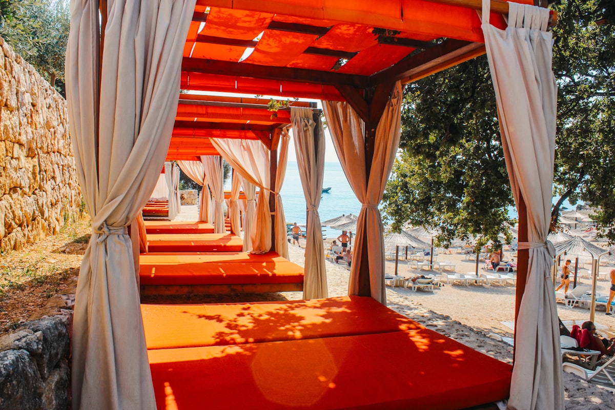 Orange lounge beds with curtains on a sunny beach related to Ultimate Outdoor Cabana Bed Experience