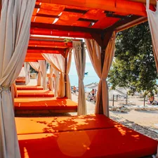 Orange lounge beds with curtains on a sunny beach related to Ultimate Outdoor Cabana Bed Experience