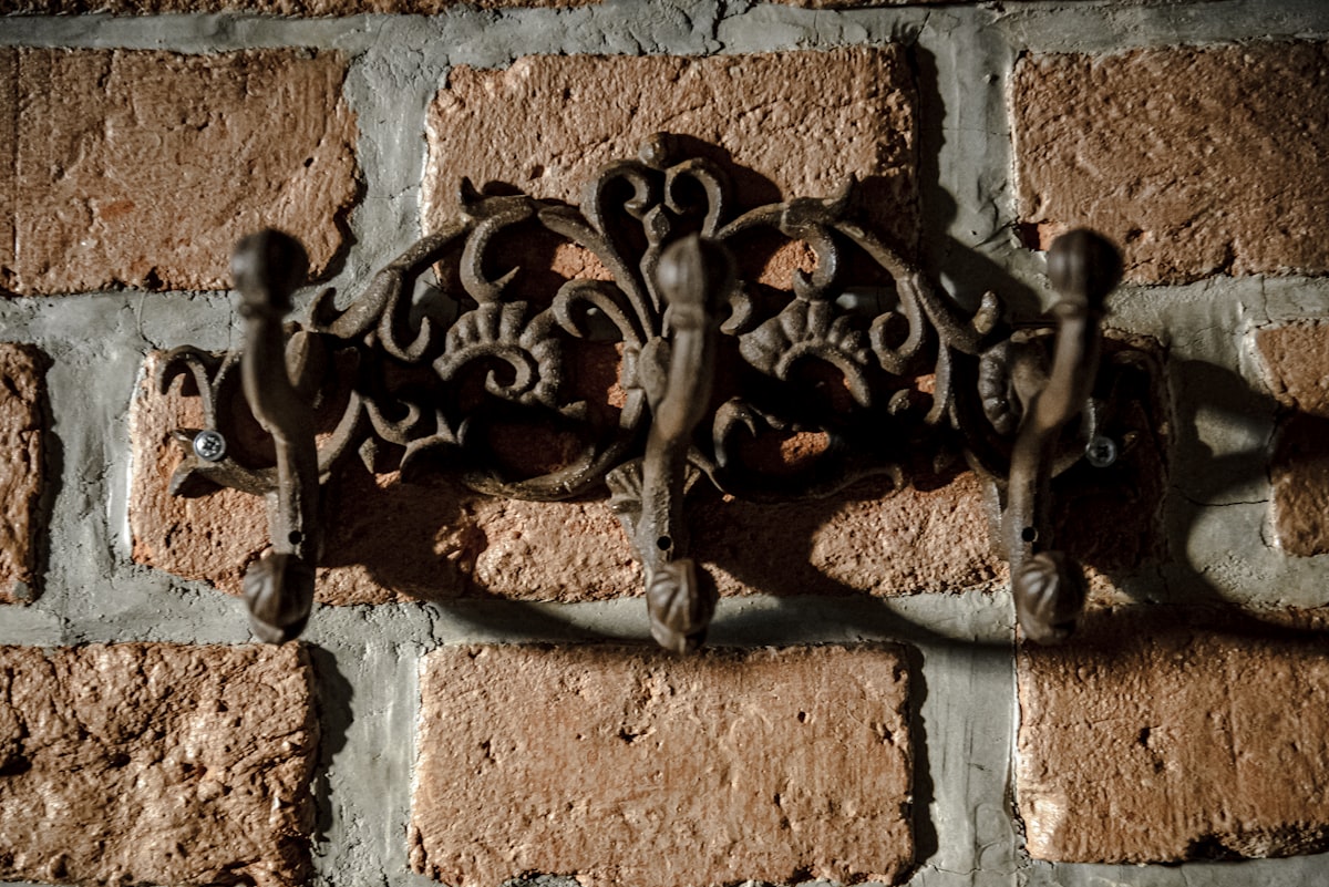Ornate metal coat rack on brick wall related to Embrace the Warmth: The Cast Iron Chiminea Experience