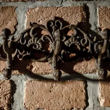 Ornate metal coat rack on brick wall related to Embrace the Warmth: The Cast Iron Chiminea Experience