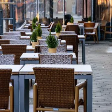Outdoor cafe tables and chairs covered in light snow. related to Warm Up Your Outdoor Space with a Chiminea: Where to Find the Perfect One