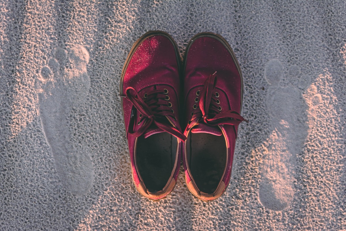 pair of red sneakers on sand related to How to Handle Bed Bugs in Shoes