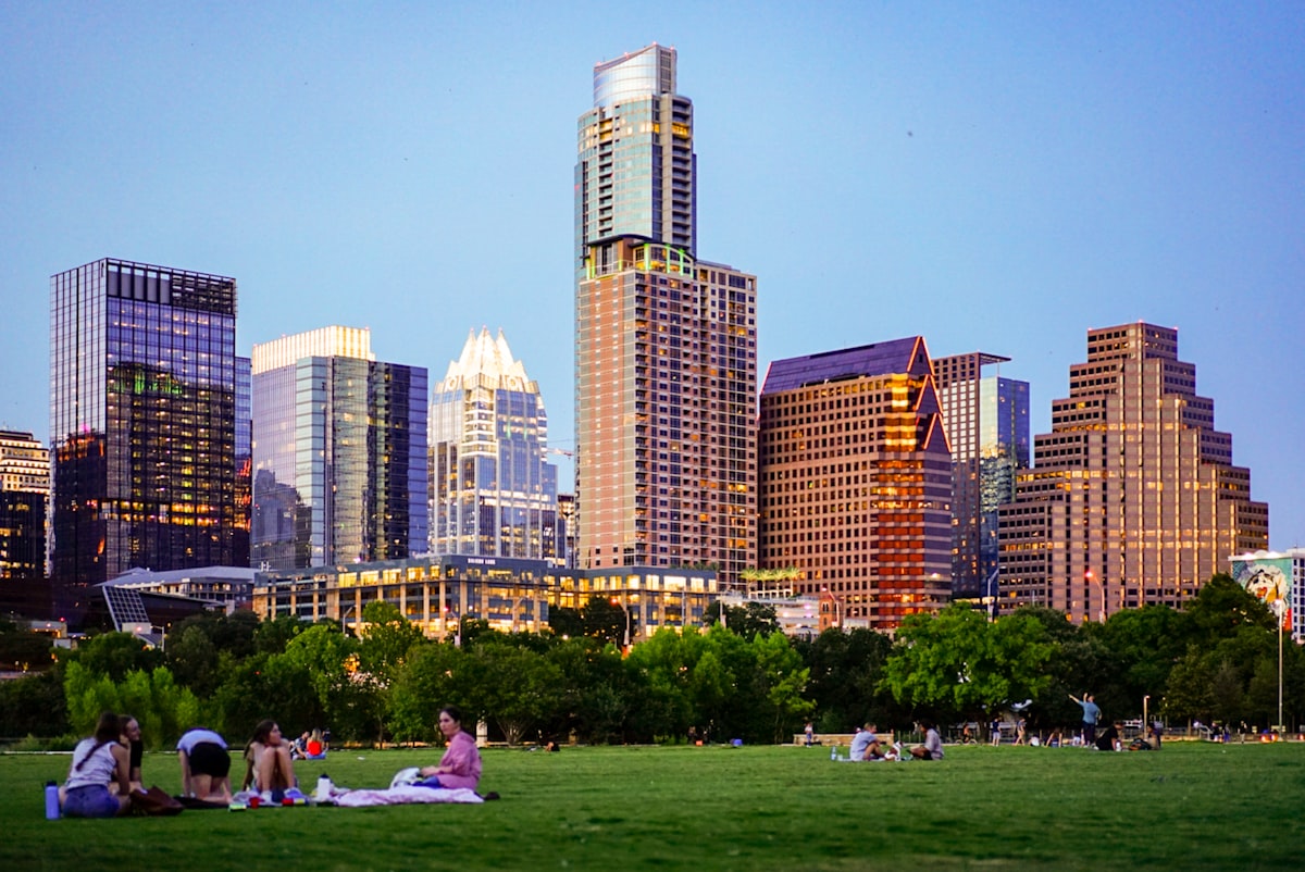 people sitting on green grass field near city buildings during daytime related to Space-Saving Solutions in Austin