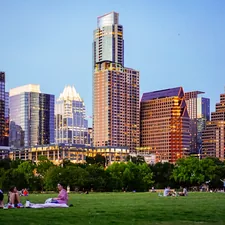 people sitting on green grass field near city buildings during daytime related to Space-Saving Solutions in Austin