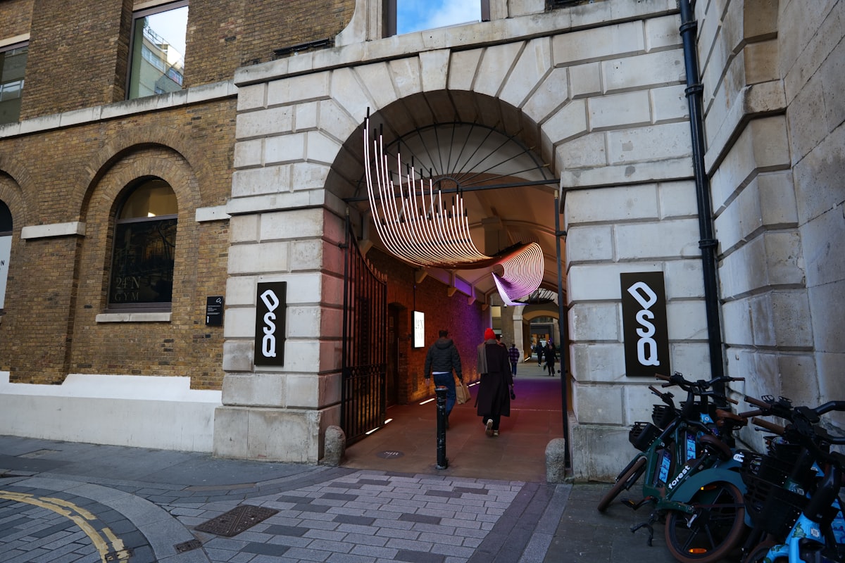 People walk through a stone archway with art installation. related to Creating a Stunning Artwork for Your Entryway