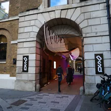 People walk through a stone archway with art installation. related to Creating a Stunning Artwork for Your Entryway