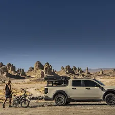 Person and bike beside truck, desert landscape with rock towers. related to Essential Accessories for Overlanding and Adventure Vehicles