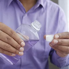 person holding white plastic bottle related to Rubbing Alcohol For Bed Bugs Treatment