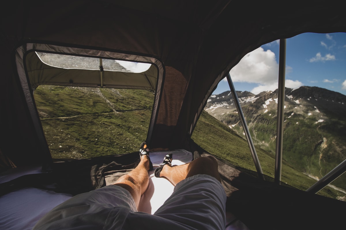 person in black pants lying on car seat related to Sleep Under the Stars: The Ultimate Guide to Beds for Camping