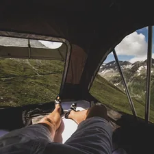 person in black pants lying on car seat related to Sleep Under the Stars: The Ultimate Guide to Beds for Camping