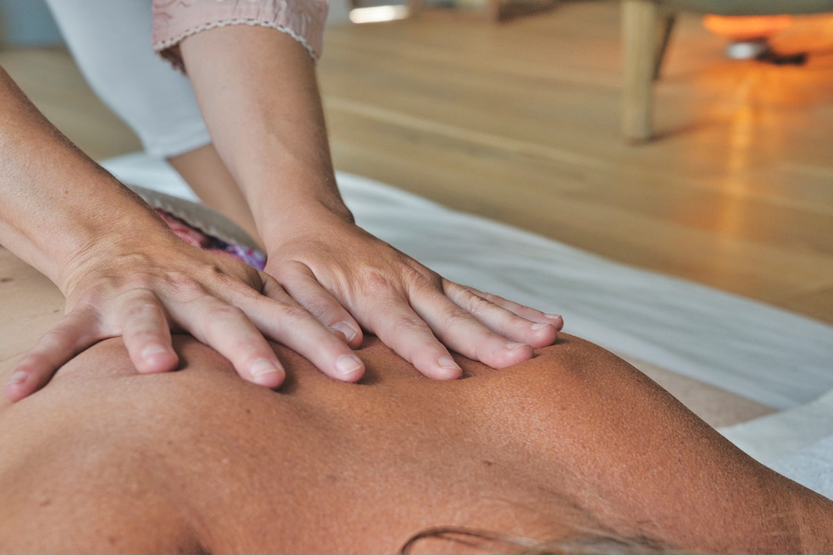 person in white shirt lying on bed related to The Benefits of Massaging Your Muscles at Planet Fitness