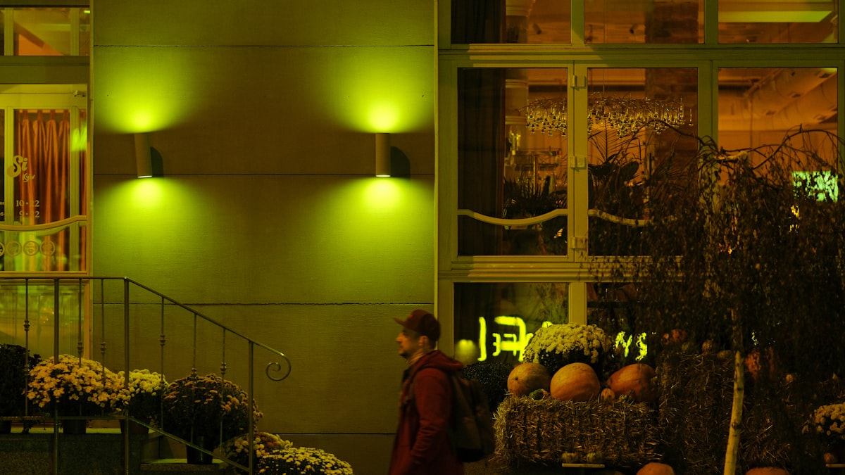 Person walks past outdoor flower display at night. related to Illuminate Your Entryway: Boosting Beauty and Safety with Outdoor Entryway Lighting