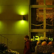 Person walks past outdoor flower display at night. related to Illuminate Your Entryway: Boosting Beauty and Safety with Outdoor Entryway Lighting