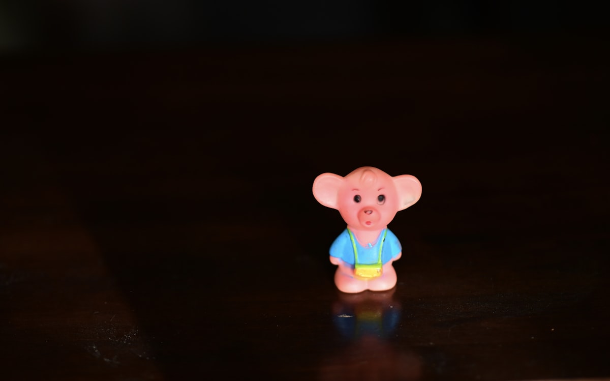 pink bear plastic toy on brown wooden table related to The Adventures of Curious George: The Ultimate Toddler Bedding Guide