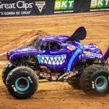 purple and black monster truck on brown sand related to Monster Jam: Bring Thrilling Racing Action to Your Bedtime