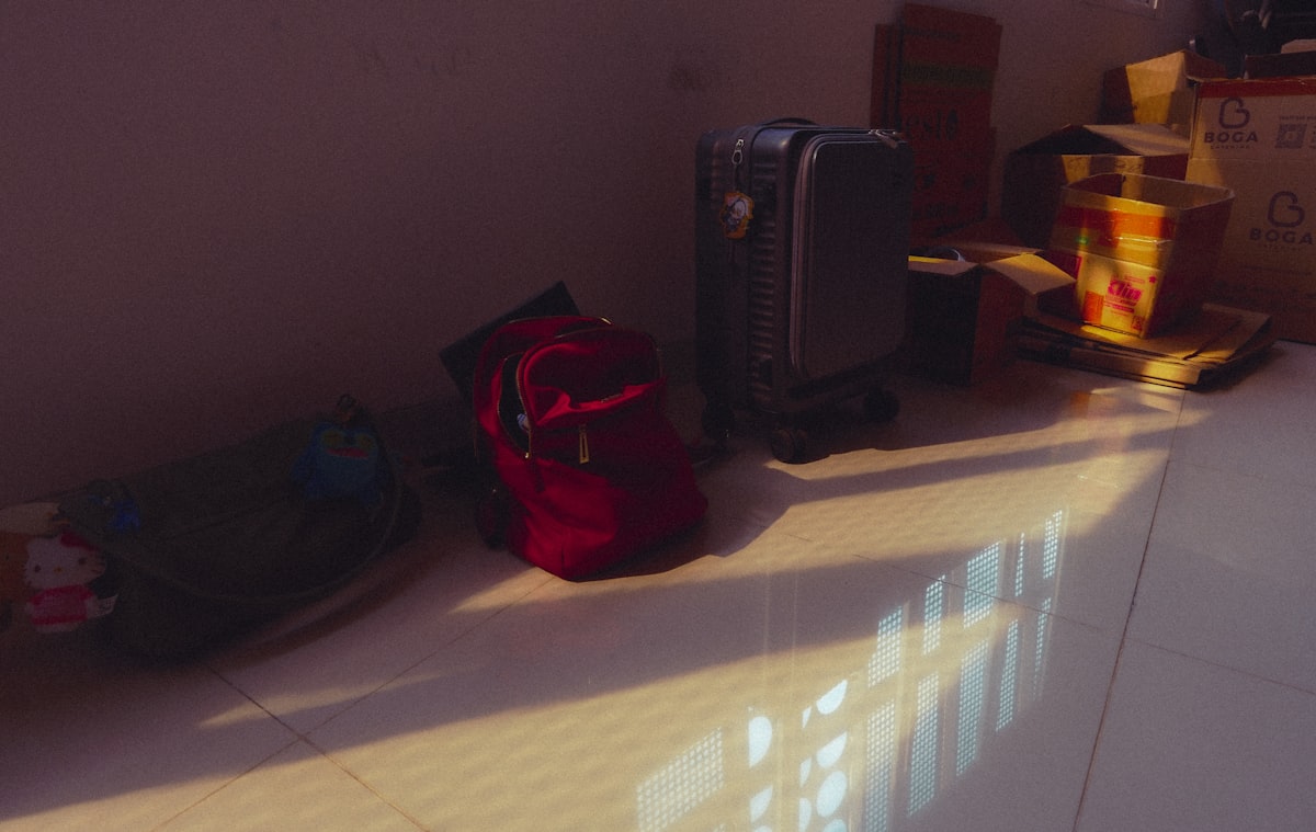 Red backpack and other bags on a sunlit floor. related to Top Picks for Luggage at Bed Bath & Beyond