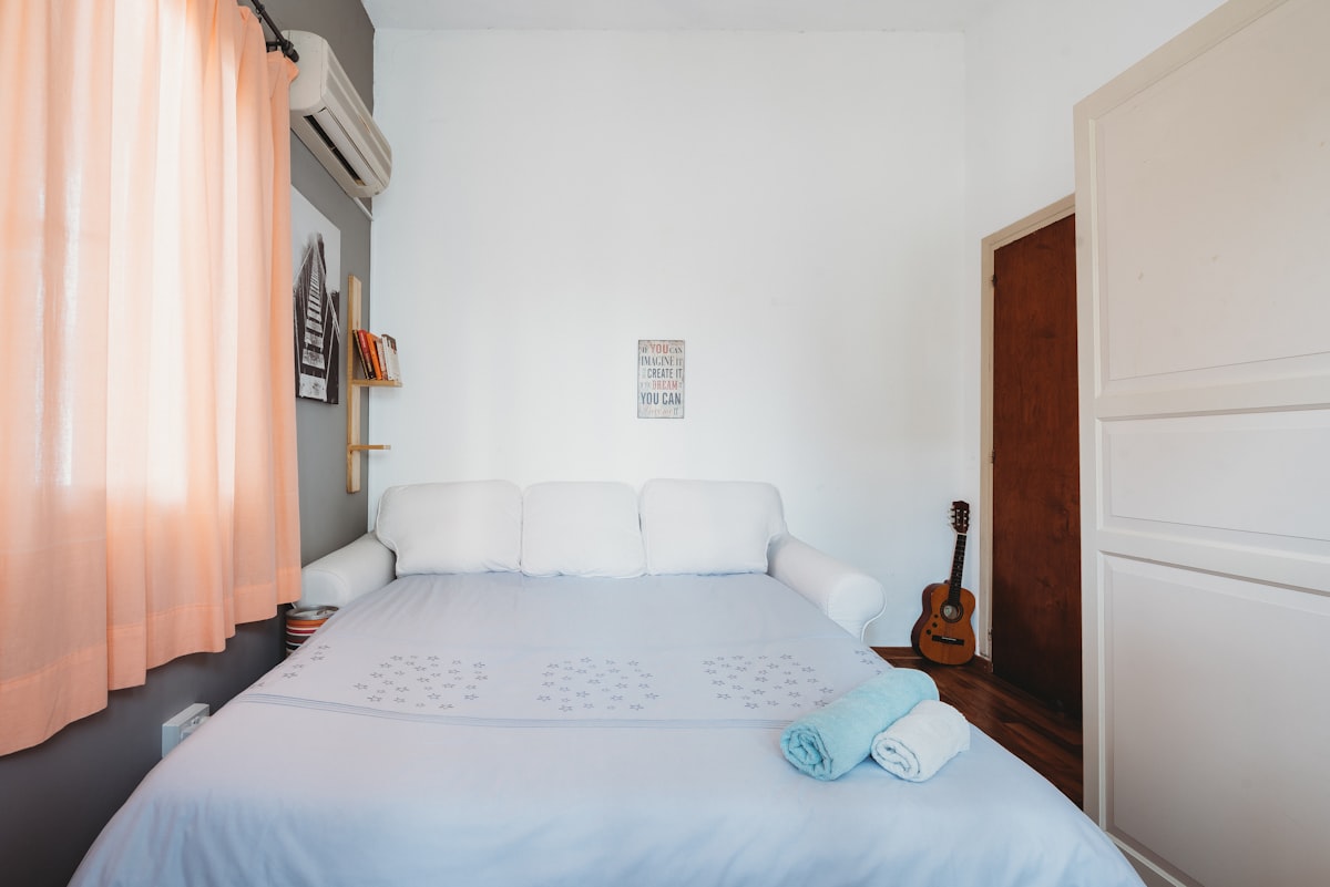 rolled blue and white towel on bed and ukulele near closed brown wooden door related to The Ultimate Guide to King Size Beds