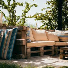 Rustic outdoor patio with pallet sofa and cushions under trees. related to How to Make a Pallet Bed: 5 Creative Ideas