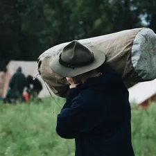selective focus photography of walking man carrying bag near set-up tent related to The Ultimate Guide to Canvas Bed Rolls