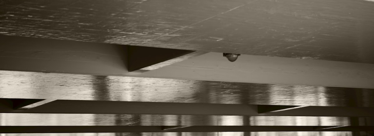 Sepia-toned industrial ceiling with a security camera. related to The Sky-High Bedroom: Innovative Ceiling-Mounted Bed Designs
