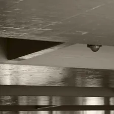 Sepia-toned industrial ceiling with a security camera. related to The Sky-High Bedroom: Innovative Ceiling-Mounted Bed Designs