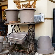 Several empty planters on an antique sewing machine base. related to Embracing the Heat: Large Cast Iron Chimineas for Your Outdoor Space