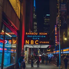 several people walking beside NBC Studios building related to Experience Ultimate Comfort at Movie Theaters with Beds in NYC