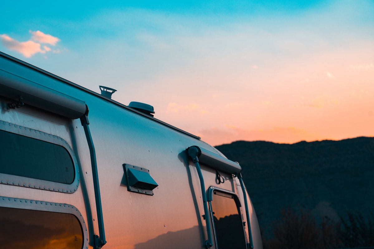 Silver travel trailer against a sunset sky. related to Cozy Up on the Open Road: The Ultimate Guide to Travel Trailer Bedding