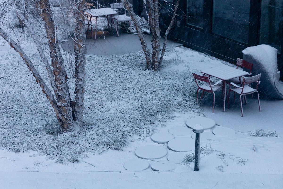 Snow covers an outdoor seating area with tables and chairs. related to Warming Your Outdoor Space with Terracotta Clay Chimineas