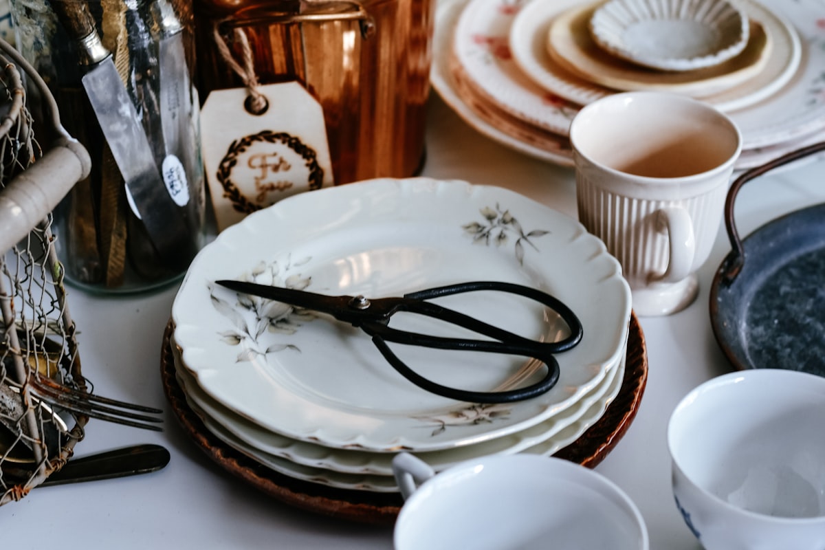 Stack of vintage plates with scissors and copper pot related to Top Styling Tools and Home Accessories