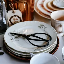 Stack of vintage plates with scissors and copper pot related to Top Styling Tools and Home Accessories