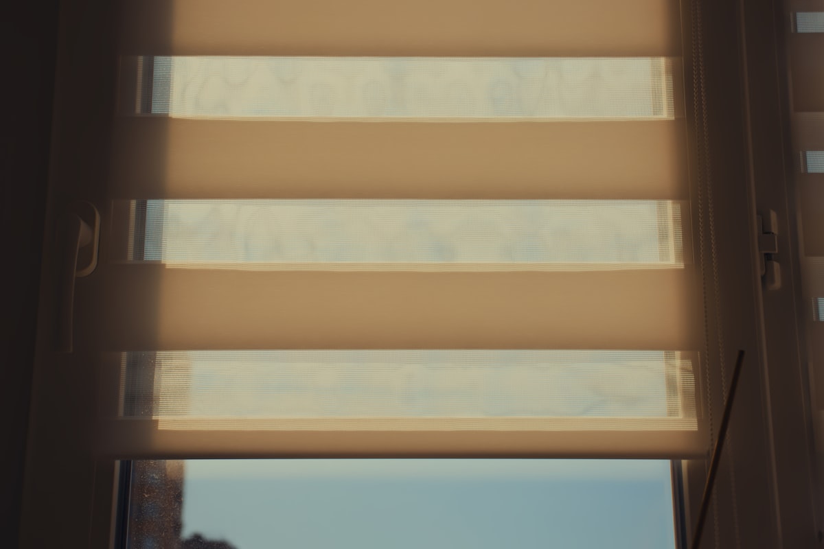 Sunlight shines through window blinds. related to Roller Shade Valances: Style and Function Combined