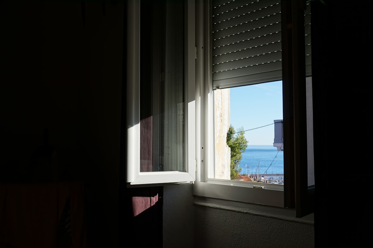 Sunlight streams through an open window onto the sea. related to Coastal Window Valances