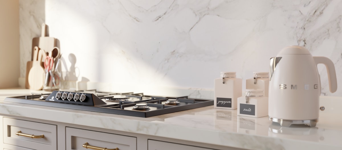 This collection of images showcases a stunning, high-end kitchen design that masterfully blends neo-classical architecture with modern luxury. The primary color palette is a soothing "greige" featured on the floor-to-ceiling cabinetry, accented by elegant brushed brass hardware. Central to the room is a large walnut-wood island topped with a thick, polished Calacatta marble slab, which is mirrored in the dramatic full-height backsplash. related to Elevate Your Kitchen Style: The Ultimate Guide to Waverly Kitchen Valances