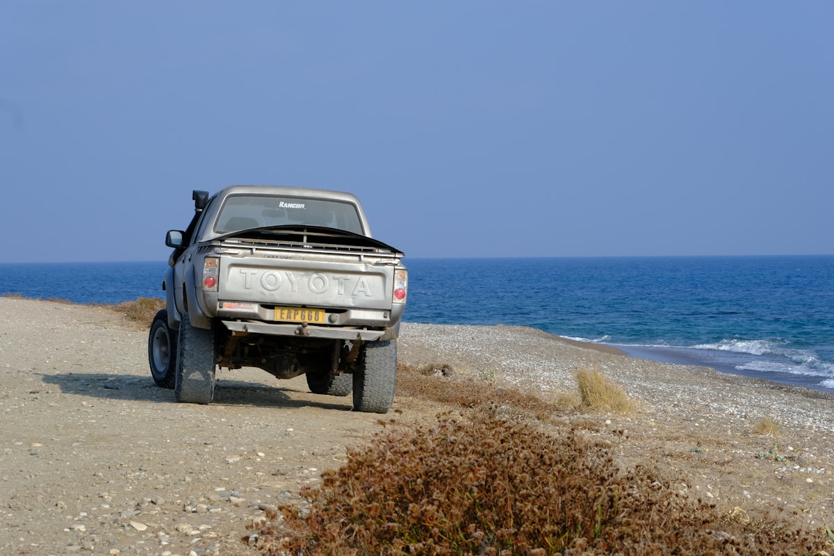 Truck parked on a dirt road by the ocean. related to Protect Your Ride: The Ultimate Guide to Bed Covers For Trucks