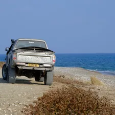 Truck parked on a dirt road by the ocean. related to Protect Your Ride: The Ultimate Guide to Bed Covers For Trucks