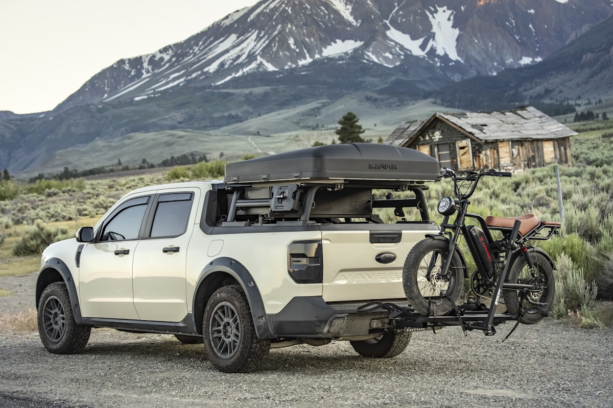 Truck with bike and rooftop tent in mountain landscape related to Protecting Your Pickup: A Comprehensive Guide to Truck Bed Caps