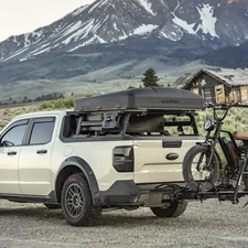 Truck with bike and rooftop tent in mountain landscape related to Protecting Your Pickup: A Comprehensive Guide to Truck Bed Caps