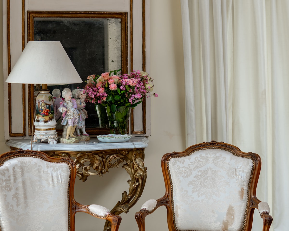two chairs and a table with a vase of flowers on it related to Statement Draperies: Embrace Elegance with Contemporary Curtain Valances