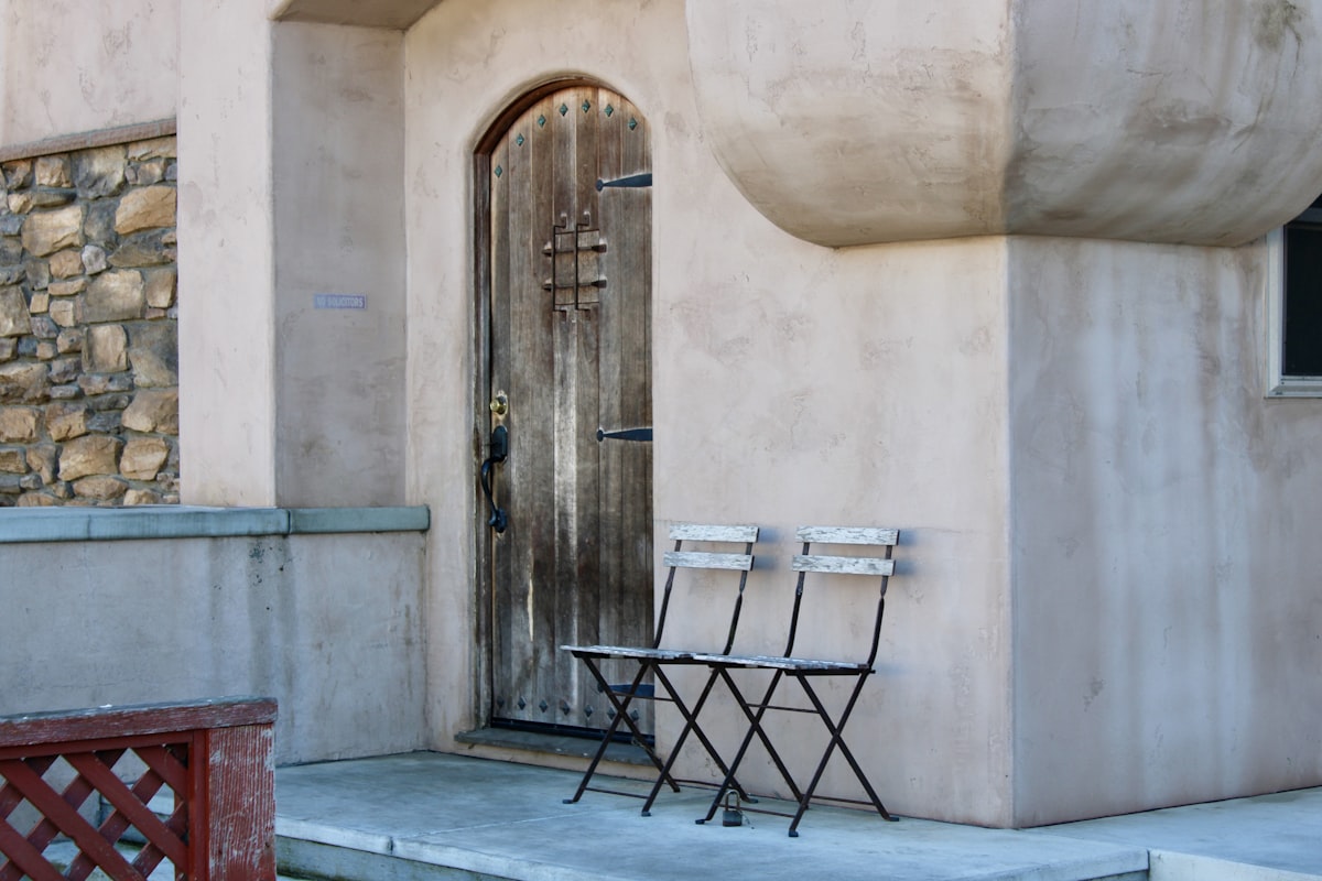 Two chairs in front of an old wooden door related to Beyond the Basics:  Unique Entryway Benches That Make a Statement