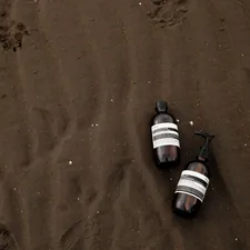 two empty beer bottles laying on a beach related to Top Tanning Bed Lotions for a Perfect Glow