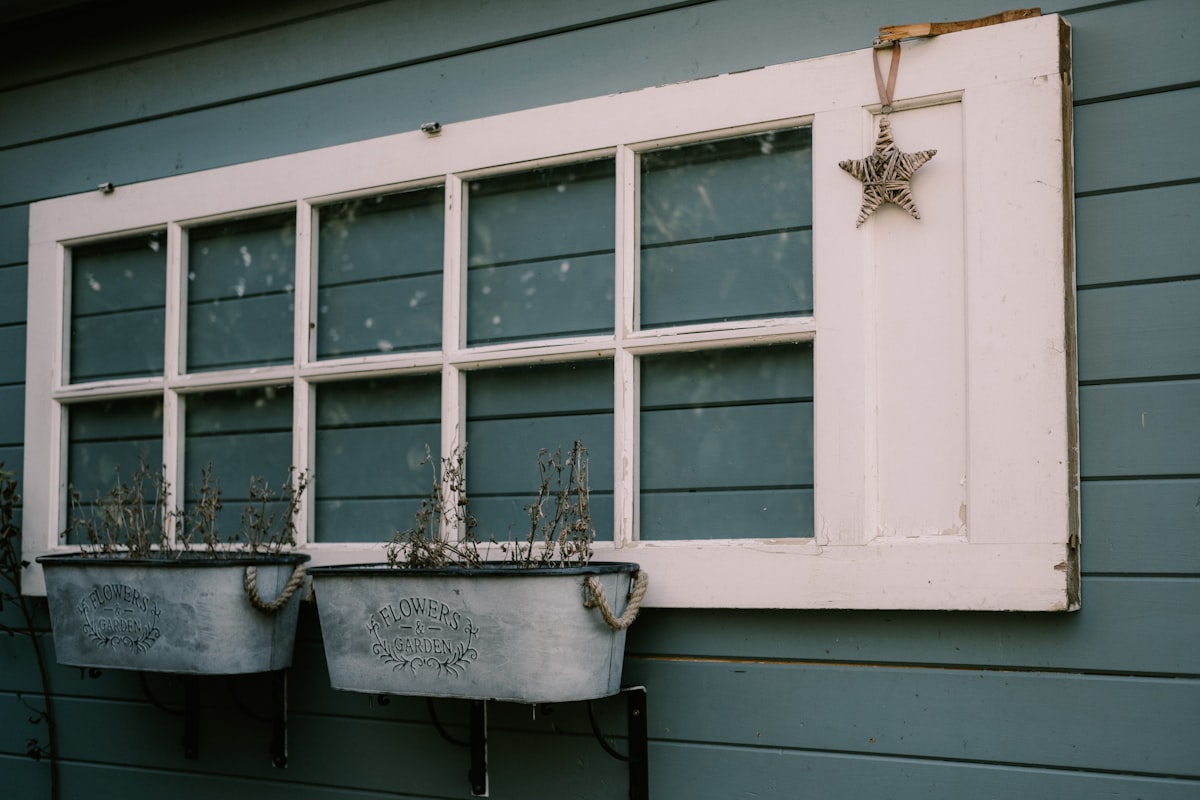 two metal planters sitting next to a window related to Elevate Your Window Style with Pottery Barn Window Valances