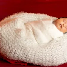 Two months old baby sleeping wrapped in white clothes. related to The Ultimate Guide to Choosing the Perfect Baby Bean Bag Bed