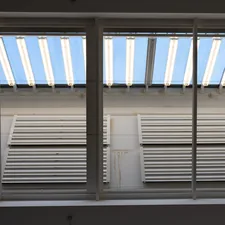 Two rows of white louvers under a striped awning. related to Mock Roman Valances