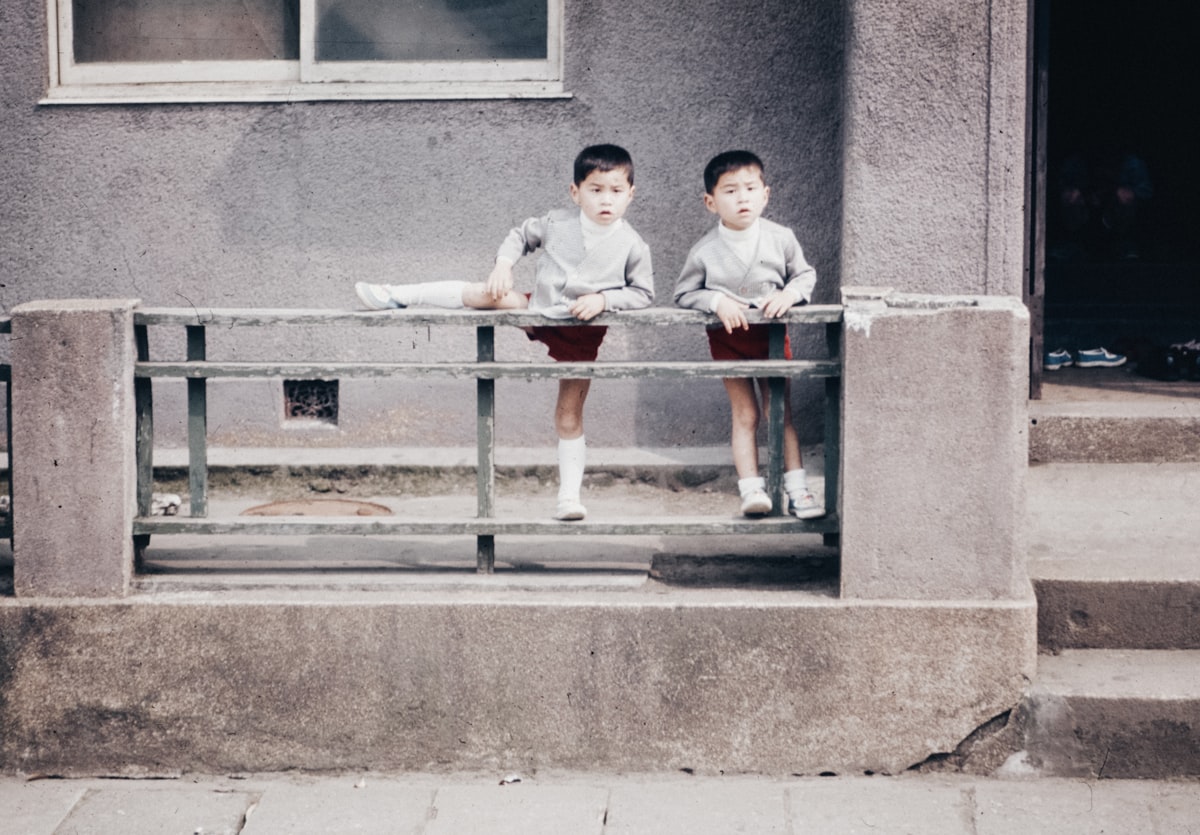Two young boys sitting on a bench in front of a building related to Understanding the Width of a Twin Size Bed