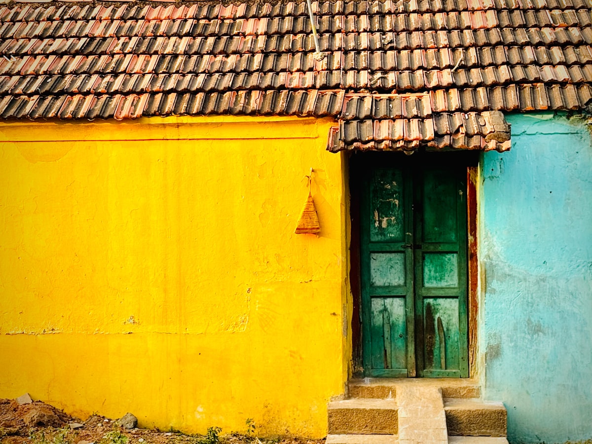Vibrant yellow and blue house with green door, tiled roof. related to 8 Timeless Paint Colors for Entryway to Make a Lasting Impression